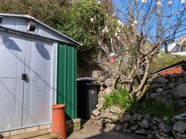 A garden area with a metal shed a flowering tree bird feeders and a stone wall at 4 Bay View Terrace in Llandudno