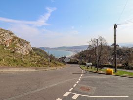 A road curving downhill towards houses with a bay and hillside in the background at 4 Bay View Terrace in Llandudno