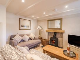 A living room with sofas cushions a wood burning stove a wooden coffee table and a television at Harbour View in Polperro