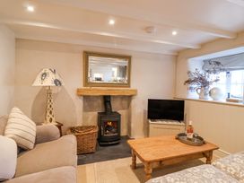 A living room with a sofa coffee table wood burning stove and television at Harbour View in Polperro
