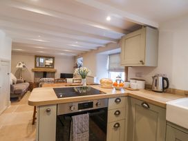 A kitchen with an oven stovetop and kettle overlooking a living area with sofas and a fireplace at Harbour View in Polperro