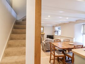 A carpeted staircase next to a dining area with a wooden table and chairs and a living room with sofas and a television at Harbour View in Polperro