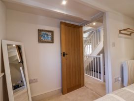 A bedroom corner with a wooden door open to a staircase and a leaning mirror on the wall at Harbour View in Polperro