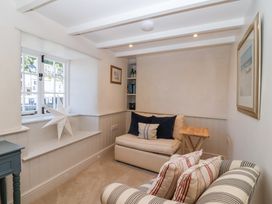 A small sitting room with a window star ornament beige and striped armchairs and a small wooden side table at Harbour View in Polperro