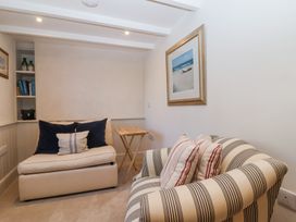 A small seating area with a striped armchair and a cream sofa with cushions and a framed beach painting on the wall at Harbour View in Polperro