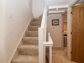 A carpeted staircase with white railing next to a hallway with wooden doors and a framed picture on the wall at Harbour View in Polperro