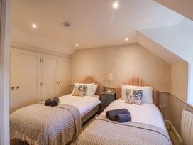 A bedroom with two single beds a bedside table and built in wardrobes at Harbour View in Polperro