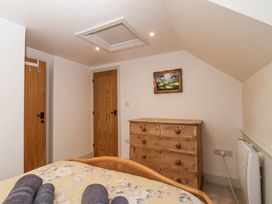A bedroom with a wooden chest of drawers a painting on the wall and two wooden doors at Harbour View in Polperro
