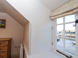 A room with a wooden chest of drawers a heater and a window overlooking a harbor at Harbour View in Polperro