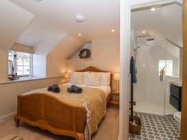 A bedroom with a wooden bed and lamps next to a bathroom with a glass shower at Harbour View in Polperro