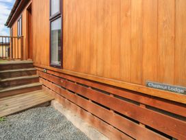 An exterior view of a wooden lodge with stairs and a gravel ground at Chestnut Lodge in Clunton near Clun