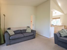 A living room with two gray sofas and a floor lamp next to a partially visible kitchen at Chestnut Lodge in Clunton near Clun
