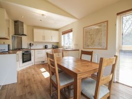 A kitchen with wooden dining table and chairs white cabinets and appliances at Chestnut Lodge in Clunton near Clun
