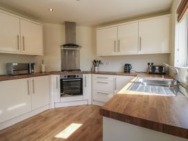A kitchen with white cabinets wooden countertops a built in oven a microwave kettle toaster and a sink at Chestnut Lodge in Clunton near Clun