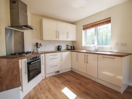 A kitchen with white cabinets wooden countertops oven stove and a window with blinds at Chestnut Lodge in Clunton near Clun