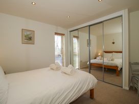 A bedroom with a bed and rolled towels on it a window a wall mirror and a chair at Chestnut Lodge in Clunton near Clun