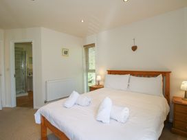 A bedroom with a double bed and rolled towels a bedside table with a lamp and an en suite bathroom at Chestnut Lodge in Clunton near Clun