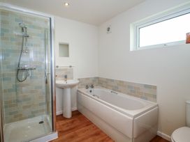 A bathroom with a shower enclosure sink bathtub and a window at Chestnut Lodge in Clunton near Clun