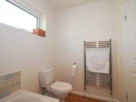 A bathroom with a toilet, a towel rack, and a small window with a basket at Chestnut Lodge in Clunton near Clun