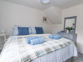 A bedroom with a bed with blue pillows and towels a dresser with a mirror and flowers at Cuddfan at Swallow Cottage in Rhydtalog near Coedpoeth
