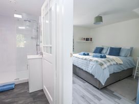 A bedroom with a bed and folded towels next to a bathroom with a shower and sink at Cuddfan at Swallow Cottage in Rhydtalog near Coedpoeth