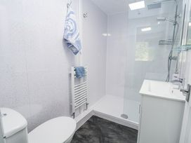 A bathroom with a toilet, towel rack, walk-in shower, and sink at Cuddfan at Swallow Cottage in Rhydtalog near Coedpoeth