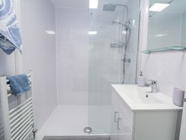 A bathroom with a walk-in shower, white sink cabinet, and blue towels on a rack at Cuddfan at Swallow Cottage Rhydtalog near Coedpoeth