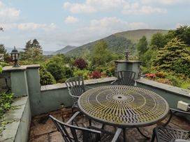 A patio with a table and chairs overlooking mountains at High Cross in Keswick