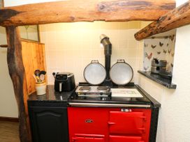 A kitchen with a red stove and cooking utensils at Dolcoed in Manordeilo near Llangadog