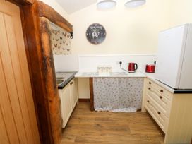 A kitchen with a sink, refrigerator, kettle, and cabinets at Dolcoed Manordeilo near Llangadog