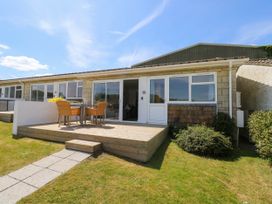A patio with table and chairs outside a single story house with sliding glass doors and windows at Cape 11 Near Yarmouth