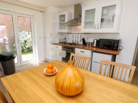 A kitchen with wooden table and chairs a wooden vase and bowl of oranges on the table white cabinets and appliances at Cape 11 Near Yarmouth
