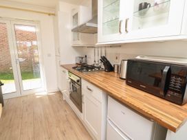 A kitchen with wooden countertops white cabinets a microwave a kettle a toaster a gas stove and glass doors leading outside at Cape 11 Near Yarmouth