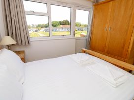A bedroom with a bed with white linens a folded towels wooden wardrobe a lamp and a window overlooking a grassy area at Cape 11 Near Yarmouth