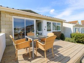 A wooden deck with a table and four wicker chairs outside a house at Cape 11 Near Yarmouth