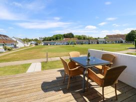 A patio with a table and four chairs overlooking a grassy area with small buildings in the background at Cape 12 Near Yarmouth
