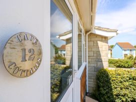 A close up of a door with a round sign that says cape 12 cottages on the wall of a house at Cape 12 Near Yarmouth