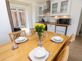 A kitchen with wooden dining table set for four with yellow flowers and white dishes at Cape 12 Near Yarmouth