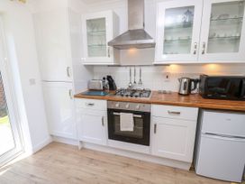 A kitchen with white cabinets wood countertops a gas stove oven toaster microwave kettle and a small refrigerator at Cape 12 Near Yarmouth