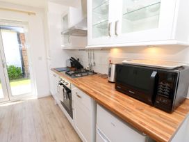 A kitchen with wooden countertop white cabinets a black microwave a gas stove a kettle and a door leading outside at Cape 12 Near Yarmouth