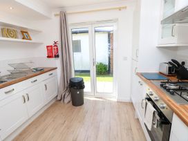 A kitchen with white cabinets wooden countertops a gas stove oven and glass doors leading outside at Cape 12 Near Yarmouth