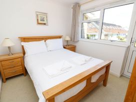 A bedroom with a wooden double bed two bedside tables with lamps and a window showing houses outside at Cape 12 near Yarmouth