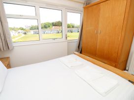 A bedroom with a bed with white linens and towels wooden wardrobe and window with a view at Cape 12 Near Yarmouth