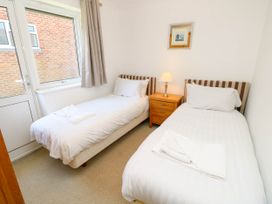 A bedroom with two single beds a wooden nightstand a lamp and a window at Cape 12 Near Yarmouth
