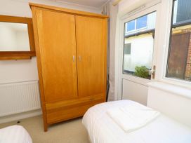 A bedroom with a wooden wardrobe a bed with folded towels a window and a door showing an outside view at Cape 12 Near Yarmouth