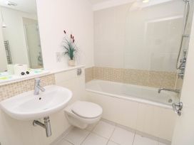 A bathroom with a sink toilet and bathtub with showerhead and a plant on the countertop at Cape 12 Near Yarmouth