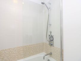 A bathroom shower area with white and beige tiled walls and a silver showerhead and faucet at Cape 12 Near Yarmouth