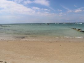 A sandy beach with gentle waves and multiple boats anchored in the water near Cape 12 Near Yarmouth