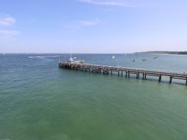 A wooden pier extending over the water with sailboats and a shoreline in the background at Cape 12 Near Yarmouth