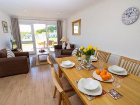 A dining table set with dishes and glasses next to a living area with sofas and a coffee table at Cape 14 in Yarmouth